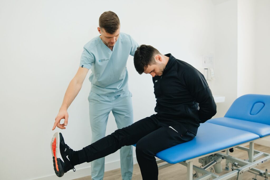 Physiotherapist assessing a patient with sciatica pain during a lower back and leg examination